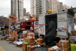 Delivery workers sort out parcels piling up at a pickup point outside residential apartment buildings closed off to non-residents following the coronavirus outbreak in Beijing, March 2, 2020.