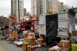 Delivery workers sort out parcels piling up at a pickup point outside residential apartment buildings closed off to non-residents following the coronavirus outbreak in Beijing, March 2, 2020.