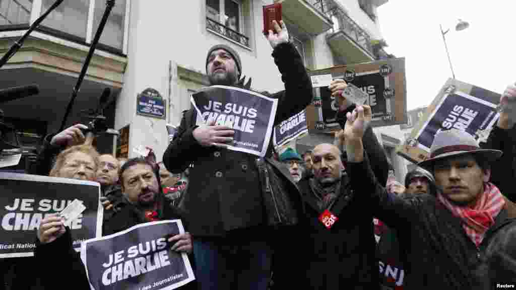 Journalists hold placards that read "I am Charlie" and their press cards during a minute of silence in front of the Paris offices of weekly satirical newspaper Charlie Hebdo in Paris, Jan. 8, 2015.
