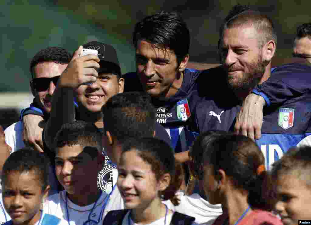 Les footballeurs italiens Gianluigi Buffon et Daniele De Rossi posent pour un selfie avec un enfant au centre d&#39;entraînement de Portobello, à Mangaratiba, le 17 juin 2014.