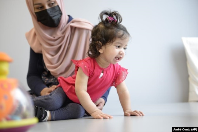 In this photo provided by the Children's Hospital of Eastern Ontario, Ayla Bashir sits with her mother, Sobia Qureshi, during a physical therapy assessment for Ayla at CHEO in Ottawa on Aug. 23, 2022. (André Coutu/CHEO via AP)