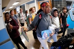 Students at Washington Junior High School leaving classes for the day use the unlocking mechanism to open the bags that contained their cell phones sealed during the school day, Thursday, Oct. 27, 2022. (AP Photo/Keith Srakocic )