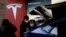 FILE - Visitors wearing face masks check a China-made Tesla Model Y sport utility vehicle (SUV) at the electric vehicle maker's showroom in Beijing, China, Jan. 5, 2021.