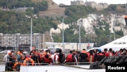 FILE - Migrants arrive at Dover harbor onboard a Border Force vessel, after being rescued while attempting to cross the English Channel, in Dover, Britain, Aug. 24, 2022.