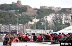 FILE - Migrants arrive at Dover harbor onboard a Border Force vessel, after being rescued while attempting to cross the English Channel, in Dover, Britain, Aug. 24, 2022.
