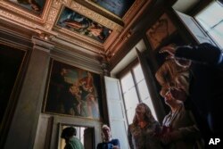 People look at the original site where the "Allegory of Inclination", top left, a 1616 work by Artemisia Gentileschi, now replaced by a photographic reproduction, before it was removed to undergo restoration, in the Casa Buonarroti Museum, in Florence, It