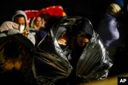 FILE - Two women from Cuba try to keep warm after crossing the border from Mexico and surrendering to authorities to apply for asylum, near Yuma, Arizona, Nov. 3, 2022.