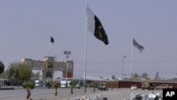 FILE - Pakistan and Taliban flags are seen on their respective sides near Friendship gate at a border crossing point in Chaman, Pakistan, Aug. 27, 2021.