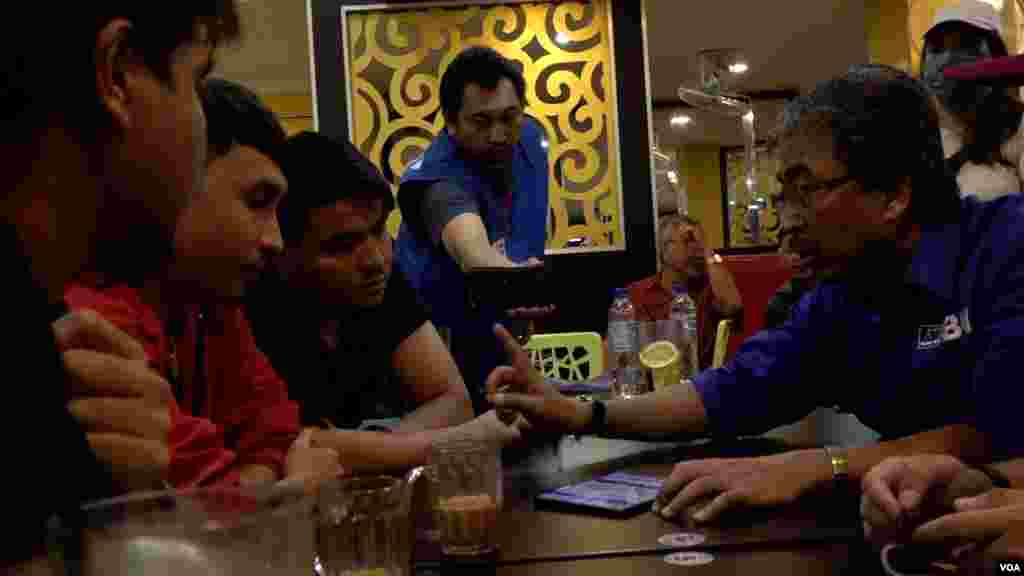 Johari Ghani, 58, right, a candidate for parliament, talks with several young voters. Conversations like these have become common on the campaign trail for the upcoming Malaysian general election. (Dave Grunebaum/VOA)