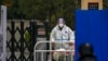 A worker in protective clothing transfers foods to a barricaded neighborhood locked down for health monitoring following a COVID-19 case detected in the area in Beijing, Nov. 9, 2022. 