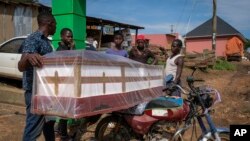 People load a coffin onto the back of a motorcycle to transport it for the burial of an Ebola victim, in the town of Kassanda, Uganda, Nov. 1, 2022.