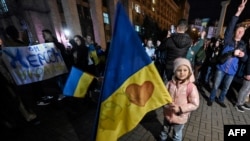 A child holds a Ukranian flag as people gather in Maidan square to celebrate the liberation of Kherson, in Kyiv on Nov. 11, 2022, amid the Russian invasion of Ukraine. 