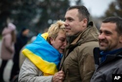 A woman leans on Ukrainian lawmaker and officer Roman Kostenko as they celebrate the recapturing in Kherson, Ukraine, Nov. 12, 2022.