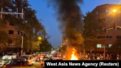 FILE - A vehicle burns during a Sept. 19, 2022 protest of the death of Mahsa Amini, who died after being arrested by "morality police" in Iran. Iran's hardline judiciary has indicted 11 people over the killing of a Basij security force member during unrest, state media reported