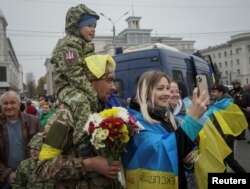 Local residents take a photo with Ukrainian serviceman as they celebrate after Russia's retreat from Kherson city, in downtown Kherson, Ukraine, Nov. 12, 2022.