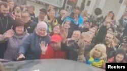 Crowds cheer Ukrainian soldiers driving by in Freedom Square in Kherson, Ukraine, in this screen grab obtained from a video released on Nov. 11, 2022. (Video handout via Reuters)