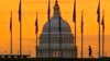 Siluet pejalan kaki dberjalan melewati bendera AS di National Mall dan melewati US Capitol Building di Washington, 7 November 2022. (Foto: AP)