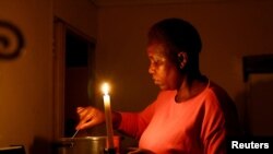 FILE: Maria Modiba cooks by a candlelight during one of the frequent power outages from South African utility Eskom, caused by its aging coal-fired plants, in Soweto, South Africa November 11, 2022. Eskom has once again forced power cuts on the nation. 