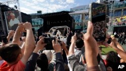 Los fieles usan sus celulares para grabar la llegada del papa Francisco (al fondo) al estadio Commonwealth de Edmonton, Canadá, antes de una misa al aire libre el 26 de julio de 2022.