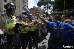 Supporters of Venezuela's opposition (R) face riot police officers who are blocking a street, as they take part in a rally to demand a referendum to remove Venezuela's President Nicolas Maduro, in Caracas, Venezuela, Sept. 16, 2016.