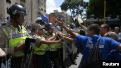 FILE - Supporters of Venezuela's opposition (R) face riot police officers who are blocking a street, as they take part in a rally to demand a referendum to remove Venezuela's President Nicolas Maduro, in Caracas, Venezuela, Sept. 16, 2016. 