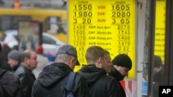 FILE - People stand in line at a currency exchange kiosk in Kyiv, Ukraine.