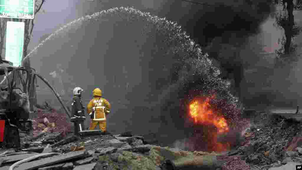 Firemen put out fire on the part of a destroyed street as fire continue to burn following multiple explosions from an underground gas leak in Kaohsiung, Taiwan, Aug. 1, 2014. 