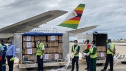 FILE - Health officials guard Zimbabwe’s donation of 200,000 Sinopharm COVID-19 vaccine doses, which arrived at Mugabe International Airport in Harare on Feb. 15, 2021. The vaccines were a donation by Beijing. (Columbus Mavhunga/VOA)