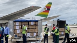 Health officials guard Zimbabwe’s donation of 200,000 Sinopharm COVID-19 vaccine doses, which arrived at the Robert Gabriel Mugabe International Airport in Harare on Feb. 15, 2021. The vaccines were a donation by Beijing. (Columbus Mavhunga/VOA)