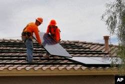 Electricians install solar panels on a roof for Arizona Public Service company in Goodyear, Arizona, July 28, 2015.