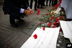 A man leaves carnations at the Saturday explosion site in Istanbul, March 20, 2016.