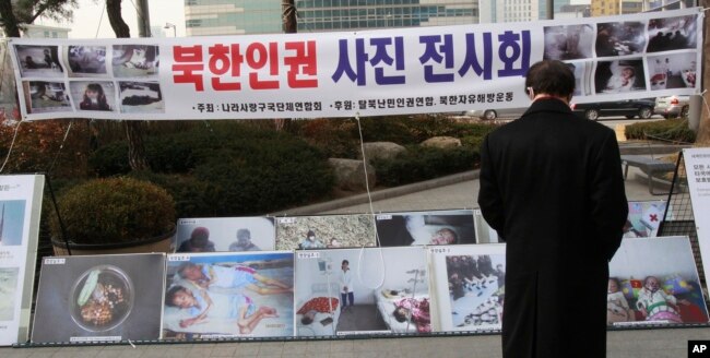 FILE - A man watches photos showing North Korean children suffering from famine at a photo exhibition in Seoul, South Korea, Feb. 27, 2014.