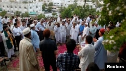 People gather at the grave of Zara Shahid Hussain, a senior politician from the Tehreek-e-Insaf political party headed by cricketer-turned-politician Imran Khan, during her funeral in Karachi, May 19, 2013. 