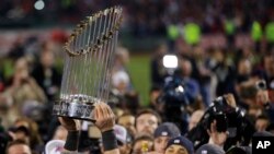 ນັກກິລາຄົນນຶ່ງ ຂອງທີມ Red Sox ແຫ່ງນະຄອນ Boston ຍົກລາງວັນຊະນະເລີດ ແຊ້ມ Baseball ຂຶ້ນ ຫຼັງຈາກເອົາຊະນະ ທີມ Cardinals ແຫ່ງນະຄອນ St. Louis (30 ຕຸລາ 2013)