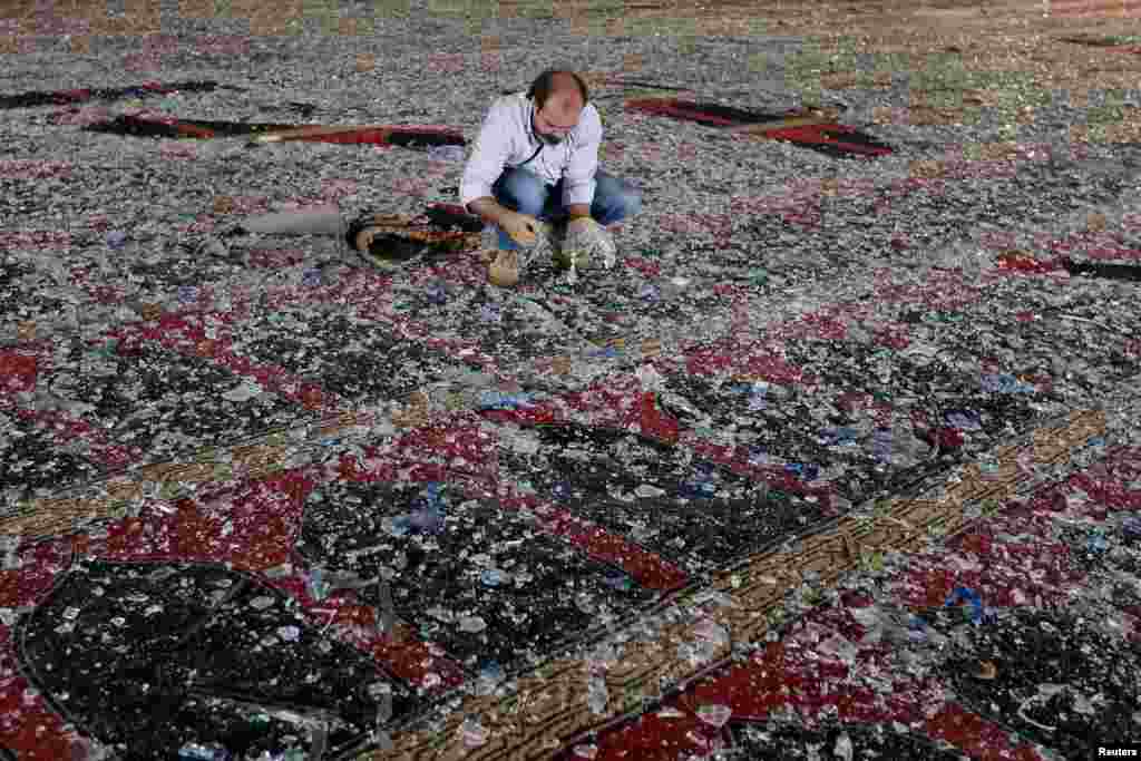 A man removes broken glass scattered on the carpet of a mosque damaged in Tuesday&#39;s blast in Beirut, Lebanon.