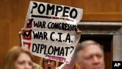 Retired U.S. Army Col. Ann Wright, center, protests the nomination of CIA Director Mike Pompeo, front right, for secretary of state, as he waits to testify before the Senate Foreign Relations Committee during a confirmation hearing on his nomination to be Secretary of State, Thursday, April 12, 2018 on Capitol Hill in Washington.