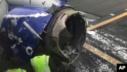 FILE - The engine on a Southwest Airlines plane is inspected as it sits on the runway at the Philadelphia International Airport after it made an emergency landing in Philadelphia, April 17, 2018. 
