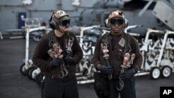 Islamic State US Carrier Photo EssayIn this Thursday, Sept. 10, 2015 photo, U.S. Navy air wing plane captains carry chains as they pause on the flight deck of the USS Theodore Roosevelt aircraft carrier.