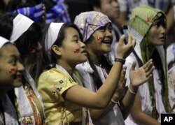 FILE - Jennifer Min, 13, photographs the stage where Burmese democracy leader Aung San Suu Kyi will speak in Fort Wayne, Indiana, Sept. 25, 2012.