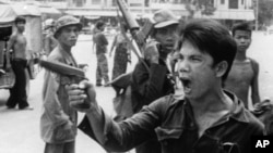 A Khmer Rouge soldier waves his pistol and orders store owners to abandon their shops in Phnom Penh, Cambodia on April 17, 1975 as the capital fell to the communist forces. A large portion of the city's population was reportedly forced to evacuate. 