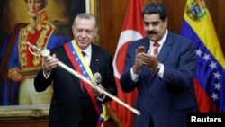 Turkish President Recep Tayyip Erdogan holds a replica of the sword of national hero Simon Bolivar, next to Venezuela's President Nicolas Maduro, during an agreement-signing ceremony between Turkey and Venezuela at Miraflores Palace in Caracas, Venezuela, Dec. 3, 2018.