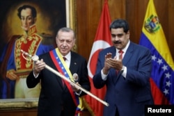 FILE - Turkish President Recep Tayyip Erdogan holds a replica of the sword of national hero Simon Bolivar, next to Venezuela's President Nicolas Maduro, during an agreement-signing ceremony between Turkey and Venezuela at Miraflores Palace in Caracas, Venezuela,