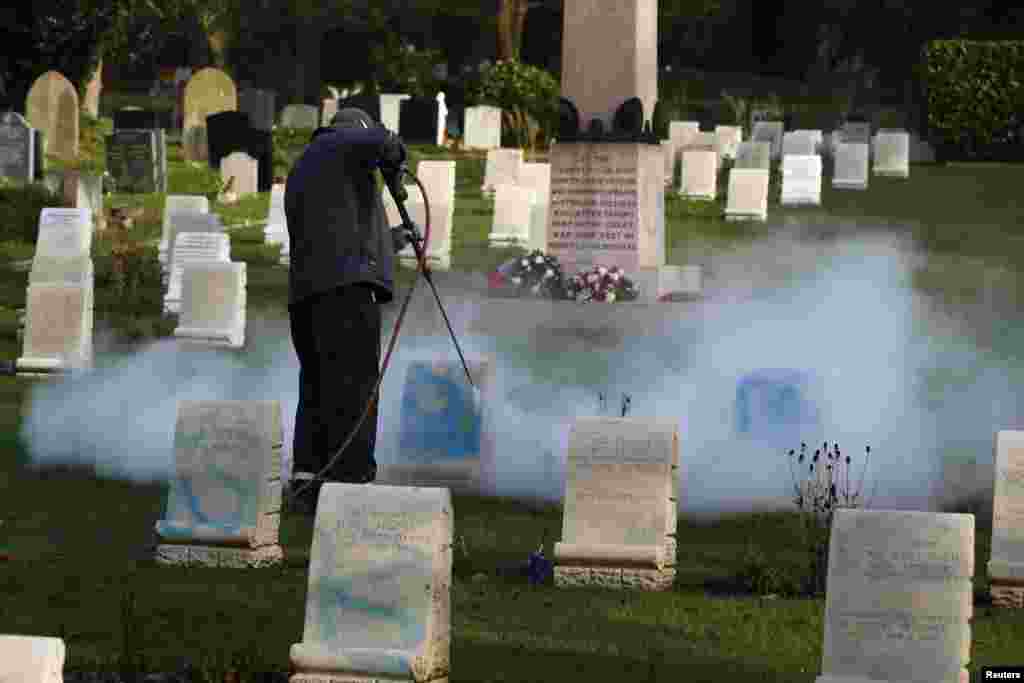A worker cleans paint off a gravestone at the Harefield churchyard in Hillingdon, Britain. Graves of Australian and New Zealand soldiers killed in World War I have been daubed with graffiti for the second time in seven months in London.