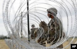 FILE - Members of a U.S Army engineering brigade place concertina wire near the U.S.-Mexico International bridge in Donna, Texas, Nov. 4, 2018.