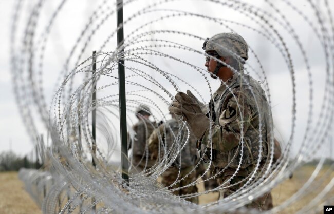 FILE - Members of a U.S Army engineering brigade place concertina wire around an encampment near the U.S.-Mexico international bridge, Nov. 4, 2018, in Donna, Texas.
