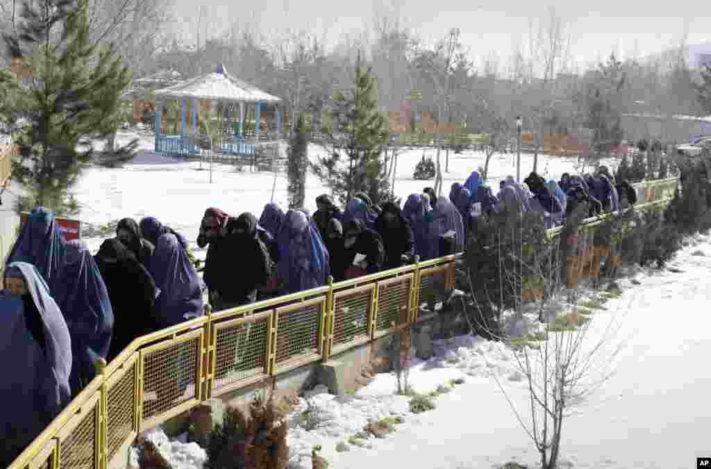 Afghan women walk to receive food and other winter assistance donated by the UNHCR in Kabul, Afghanistan, January 2, 2013. 