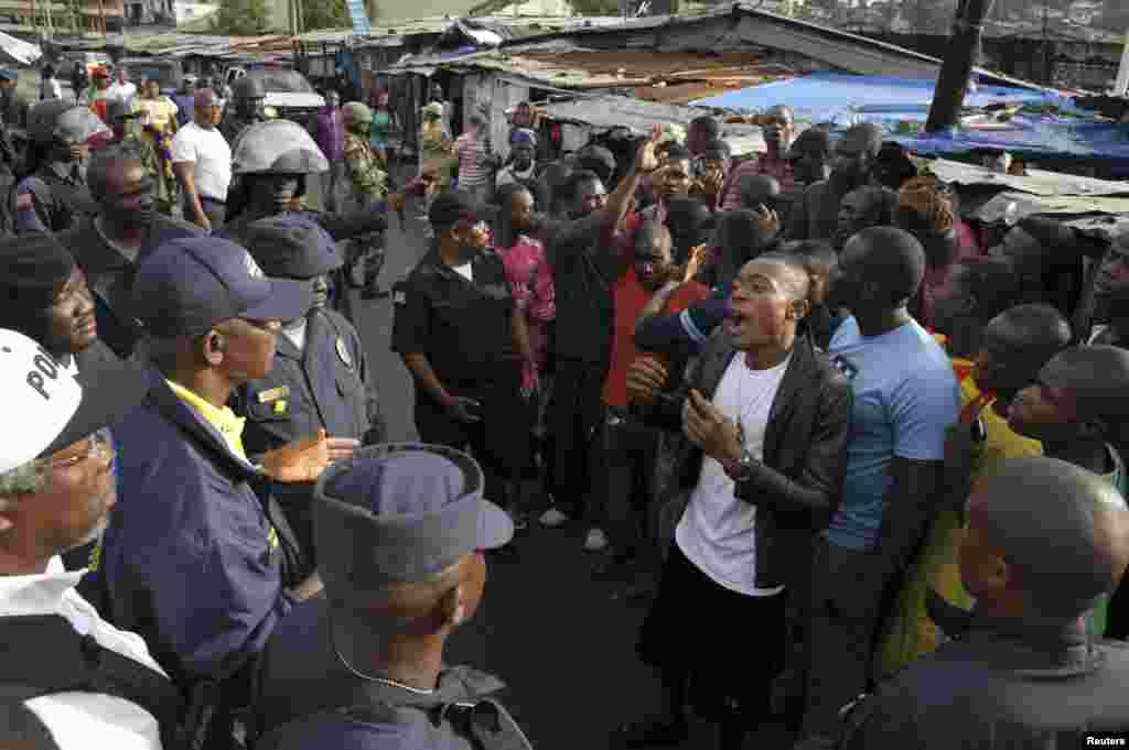 Members of Liberian security forces talk with a protester in the West Point neighborhood in Monrovia Aug. 20, 2014.