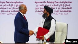 Mullah Abdul Ghani Baradar, líder de la delegación talibán y Zalmay Khalilzad, enviado de EE.UU. para la paz en Afganistán, se dan la mano después de firmar un acuerdo en Doha, Qatar, el 29 de febrero de 2020.