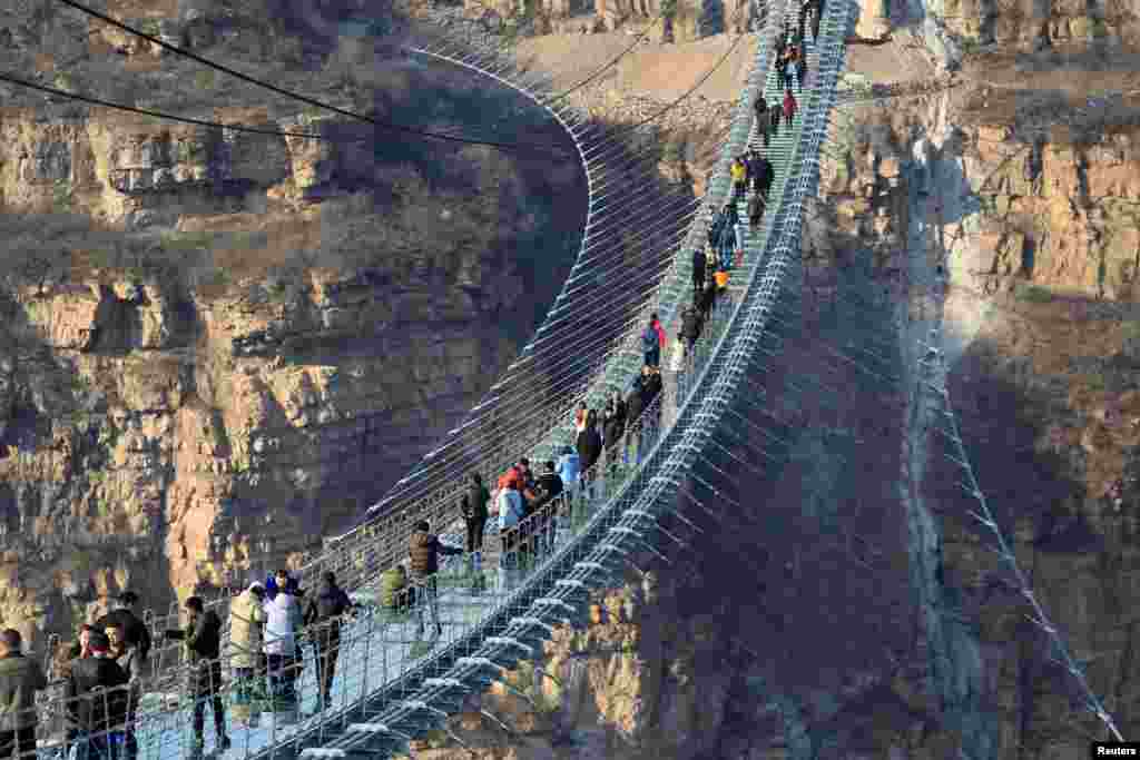 بازدیدکنندگان در حال عبور از طولانی ترین پل معلق شیشه ای در چین