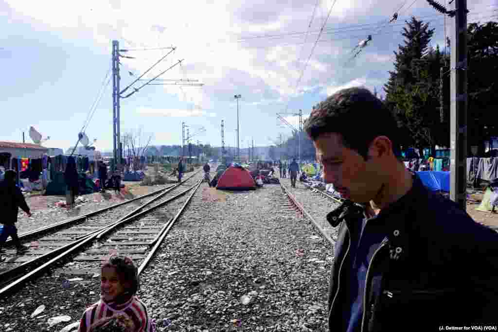 A man walks amid a makeshift encampment, with tents set up between train tracks in the northern Greek border town of Idomeni, March 4, 2016.